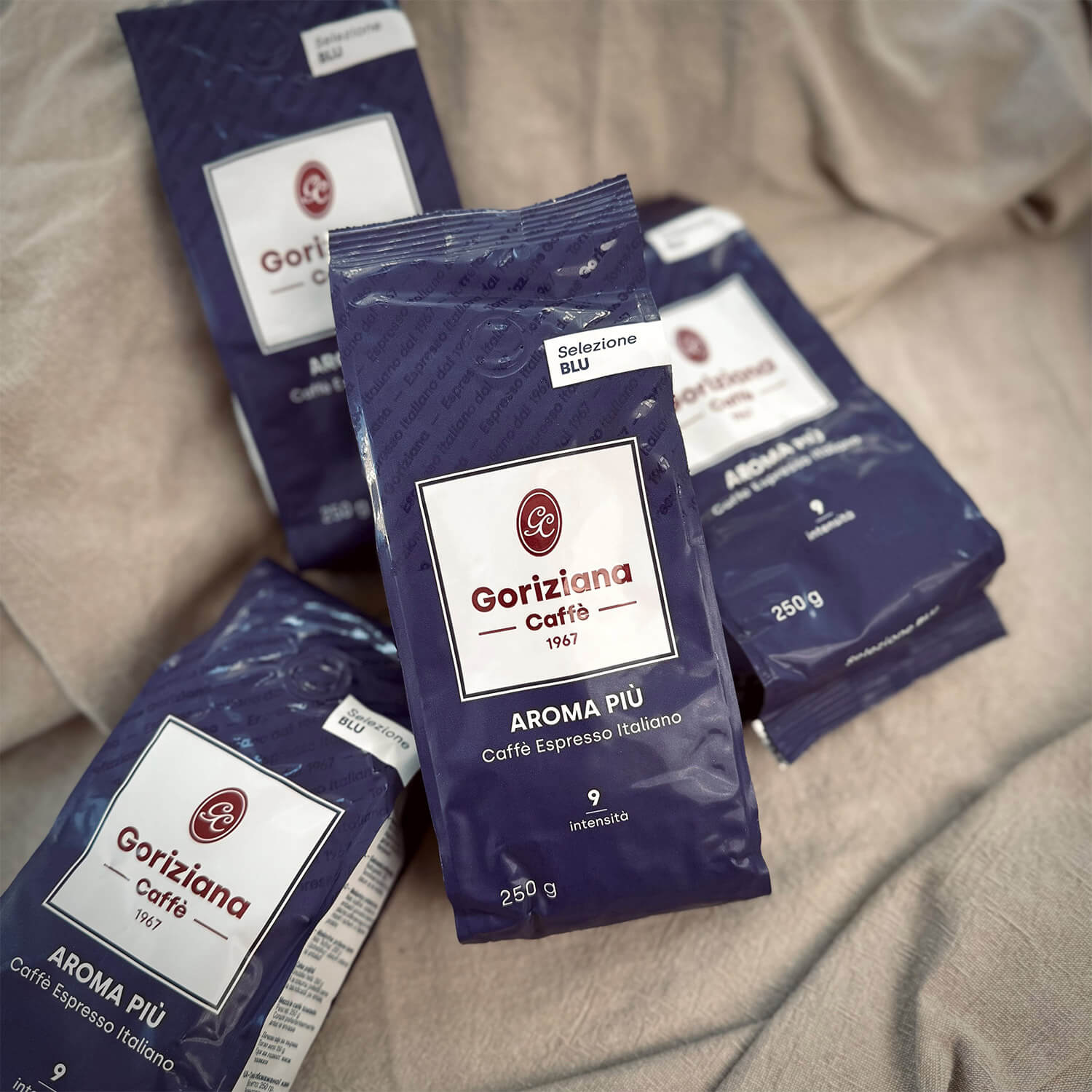 Vier Packungen Torrefazione Goriziana Espresso Bohnen BLU Aroma Piu (4 x 250g) werden auf einer leichten Stoffoberfläche präsentiert.