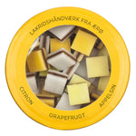 Hattesens Konfektfabrik Lakritz mit Zitrone, Orange und Grapefruit, 125 g: Runde gelbe Dose mit durchsichtigem Deckel mit quadratischen Bonbons in Weiß, Gelb und Orange; dänischer Text am Rand.