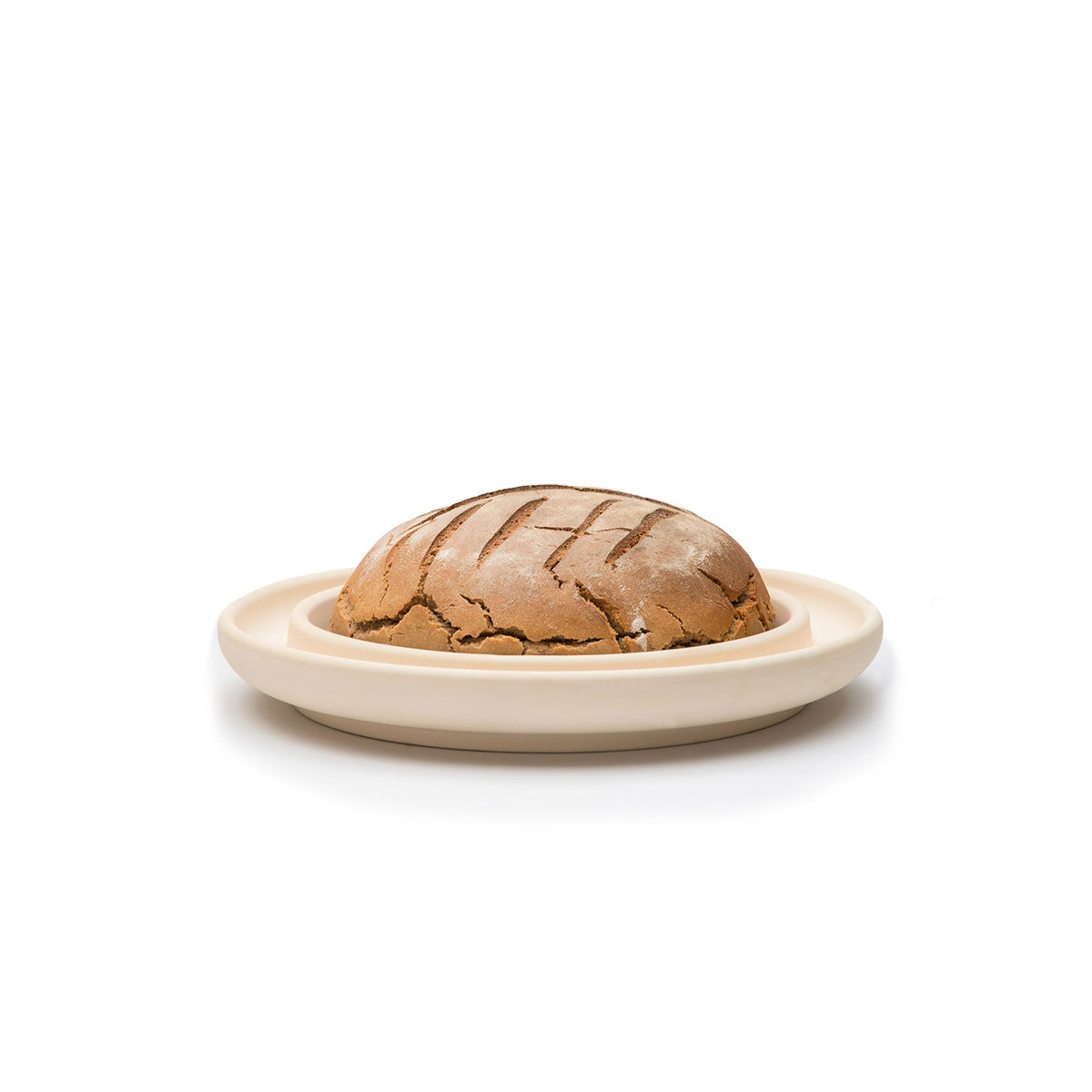 Auf der Backplatte Bread&Cake CeraFlam® von Denk Keramik liegt ein rundes Schwarzbrot mit aufgesprungener Kruste, abgebildet auf einem beigen Keramikteller vor weißem Hintergrund.
