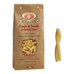 Eine braune Tüte Casareccia Hartweizennudeln von Rustichella, 500 g von Rustichella d'Abruzzo S.p.A., mit einem Stück Pasta daneben.