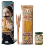 Das Rustichella d'Abruzzo Pasta Set Dali enthält Spaghetti, eine Holzgabel und Pistazienpesto in einer dekorativen Dose, die eine Frau beim Nudelessen zeigt - perfekt für den Weltnudeltag.