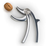 Der Odin GmbH Odin Nussknacker Cracky aus Aluminium, poliert, ist auf weißem Hintergrund mit einer Walnuss in der Nähe seiner gezackten Backen abgebildet.