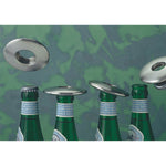 Vier Odin GmbH Flaschenöffner Disc aus Aluminium Ø 7 cm schweben über vier Glasflaschenverschlüssen vor einem grün gesprenkelten Hintergrund.