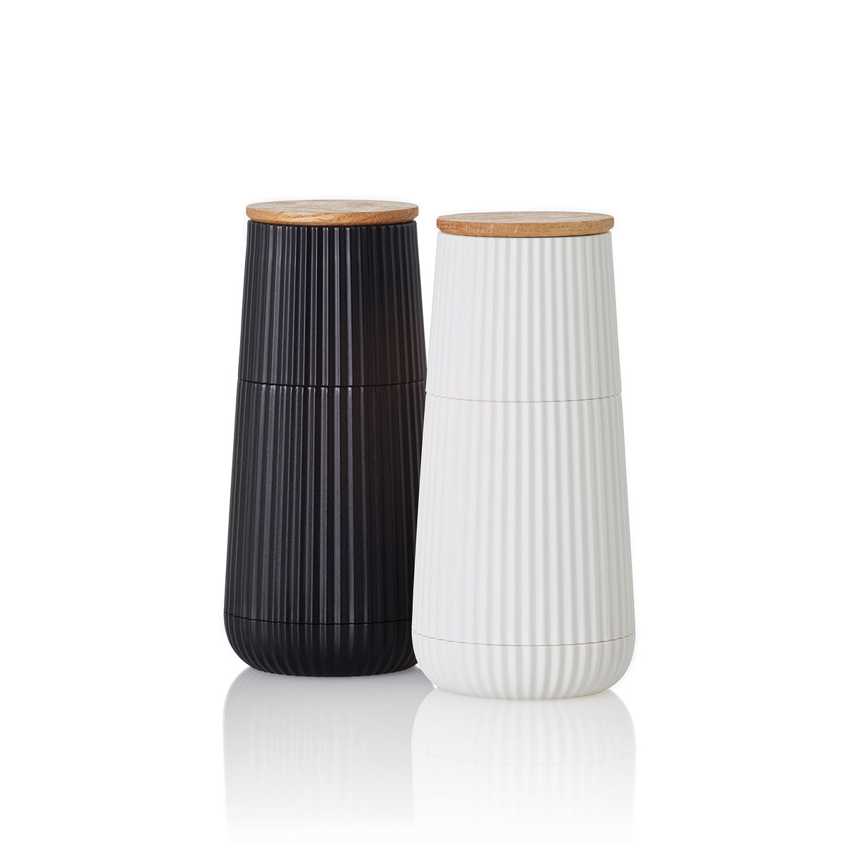 Das AdHoc Pfeffer- & Salzmühle Set Scape zeigt schwarze und weiße Rippenmühlen mit Holzdeckeln aus Eiche und Kunststoff, jeweils 12,3 cm, bestückt mit CeraCut® Keramikmahlwerken, nebeneinander auf weißem Grund.