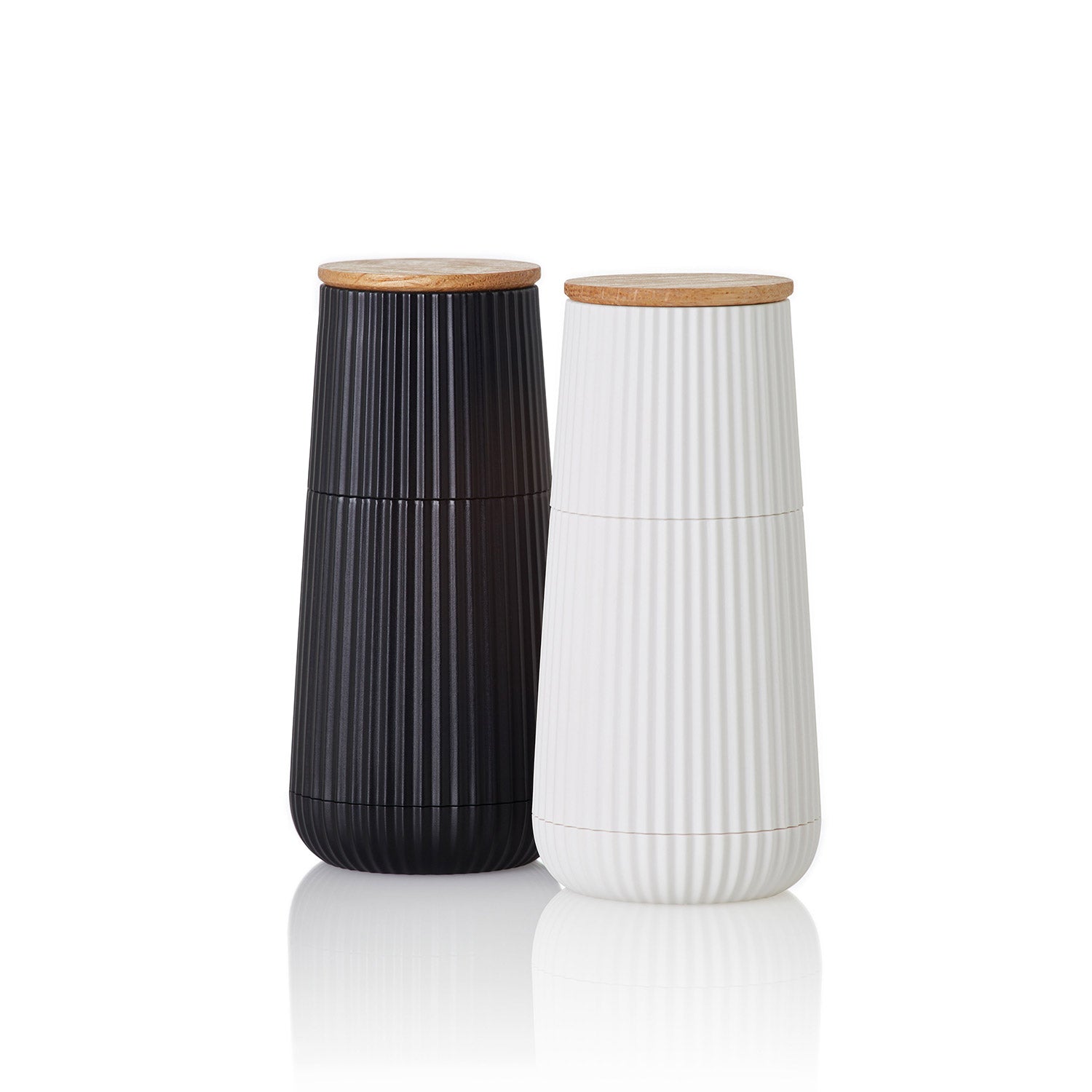 Das AdHoc Pfeffer- & Salzmühle Set Scape zeigt schwarze und weiße Rippenmühlen mit Holzdeckeln aus Eiche und Kunststoff, jeweils 12,3 cm, bestückt mit CeraCut® Keramikmahlwerken, nebeneinander auf weißem Grund.