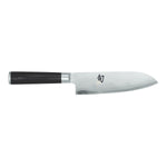 Das Kai Shun Classic Santoku-Messer 18,0 cm ist ein Kochmesser im japanischen Stil mit einem dunklen Griff und einer silbernen Klinge, die mit Wellenmustern verziert ist.