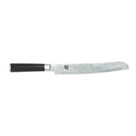 Das KAI Shun Classic Brotmesser 23,0 cm von Kai zeichnet sich durch eine gezackte, gemusterte, silberne Klinge und einen dunklen Griff aus, der auf einem weißen Hintergrund abgebildet ist.