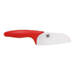 Das KAI Tim Mälzer Juniorkochmesser von Kai hat eine 11 cm lange, gezackte weiße Klinge, einen roten Griff und ein Krabbenlogo in der Nähe der Basis.