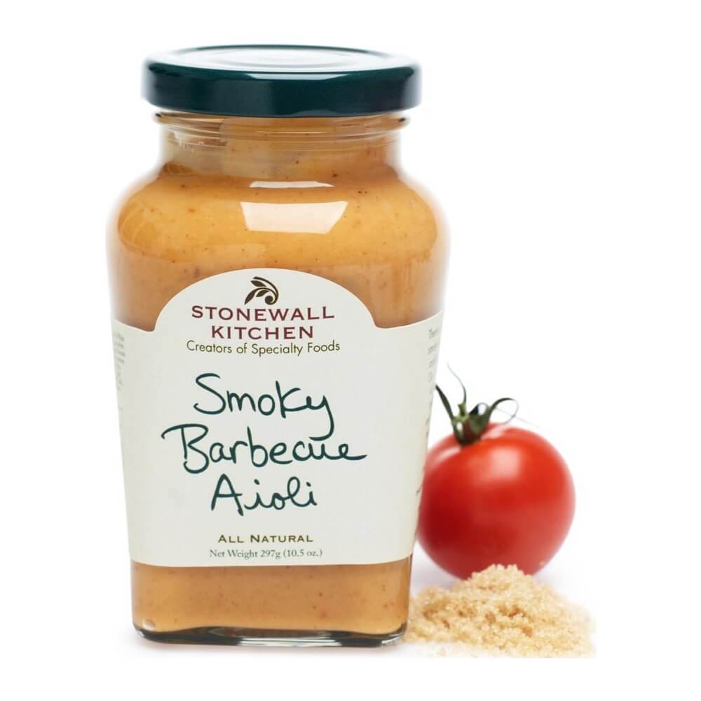Ein Glas Smoky Barbecue Aioli von Stonewall Kitchen, 305 g, steht neben einer Tomate und einem Haufen braunem Zucker.