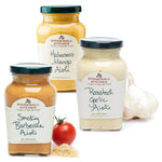 Drei Gläser des 3er Aioli Probierpakets von Stonewall Kitchen sind abgebildet, jeweils mit Geschmacksrichtungen wie Knoblauch, Tomate und braunem Zucker.