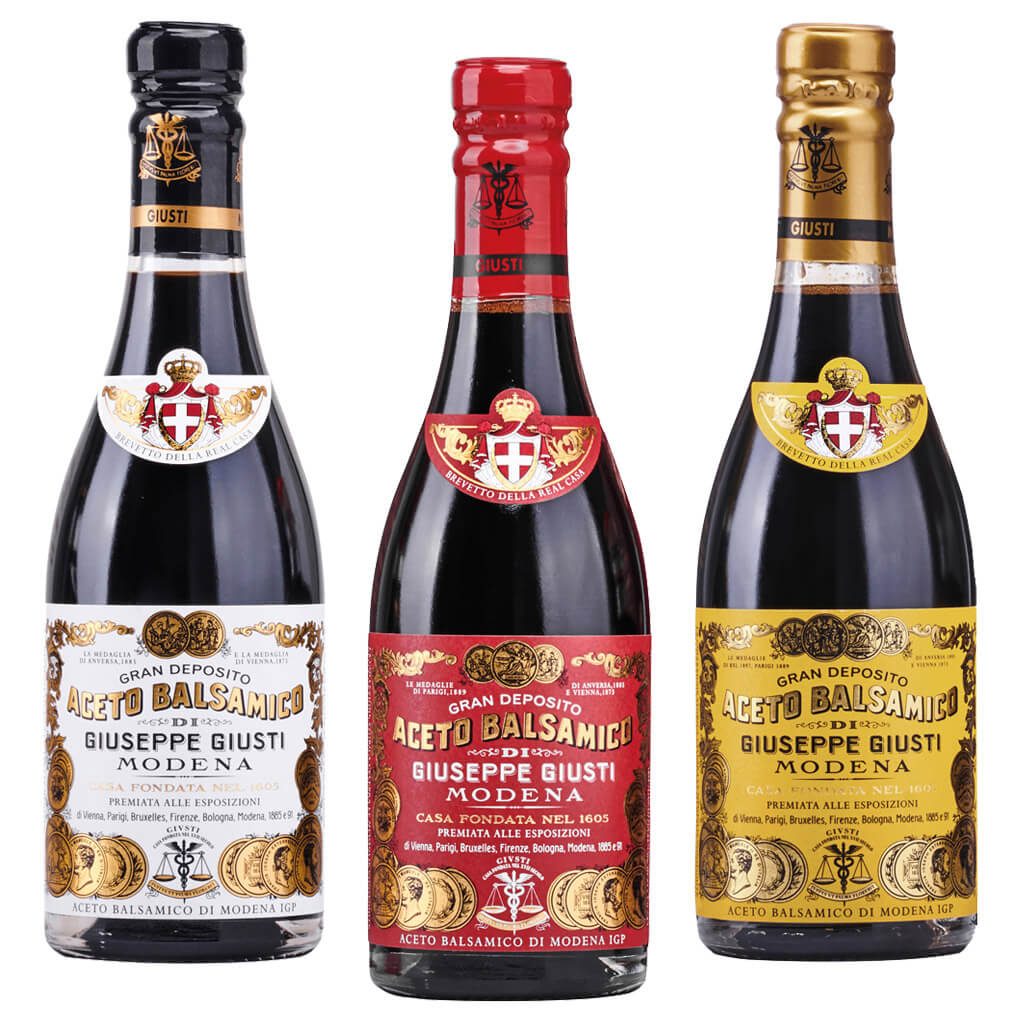 Das 3er Aceto Balsamico Probierpaket von Giuseppe Giusti (3 x 250 ml) besteht aus drei nebeneinander stehenden Flaschen mit schwarzen, roten und goldenen Etiketten.